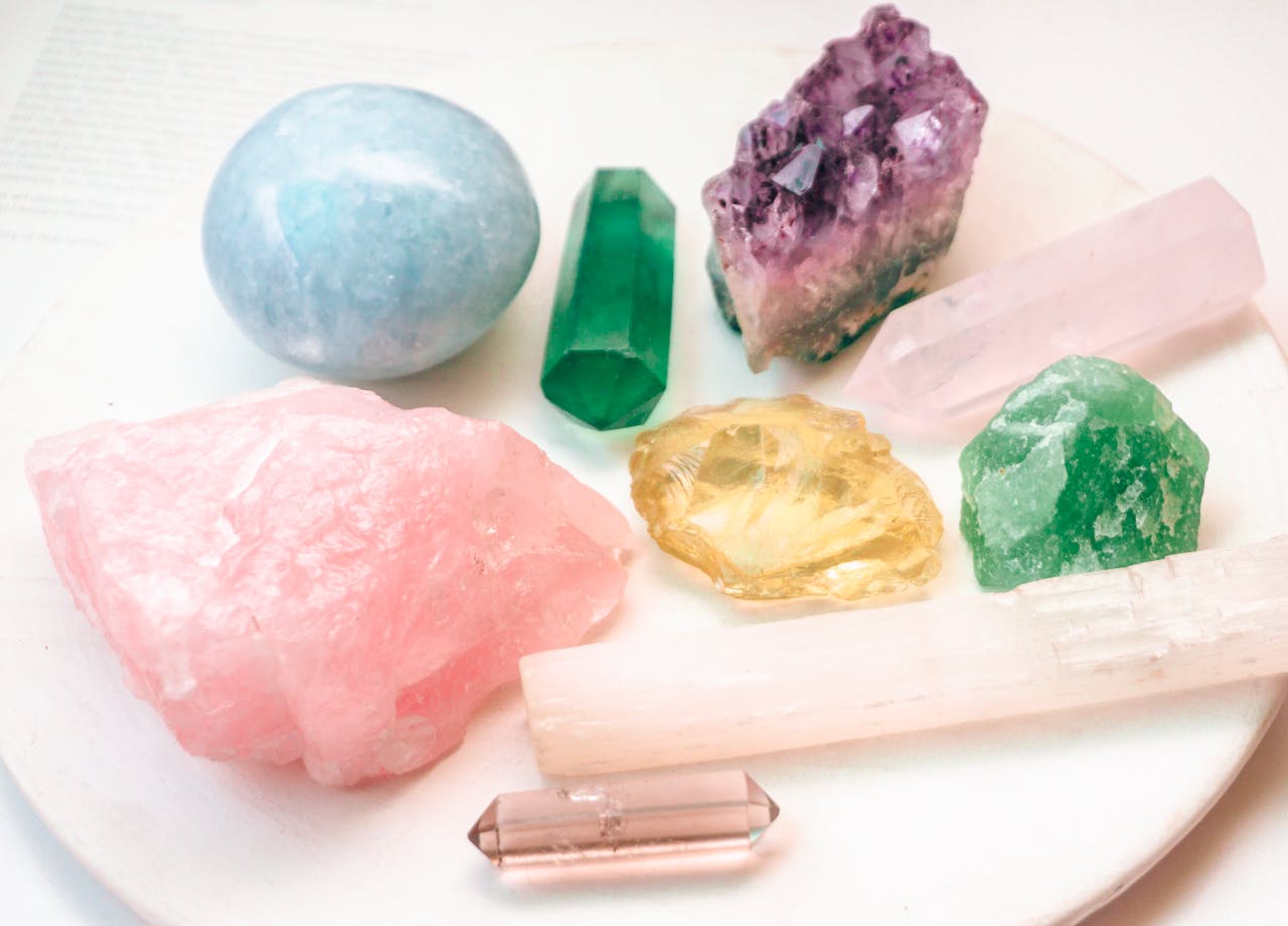 Close-up of various colorful crystals arranged on a white plate, showcasing their natural beauty.