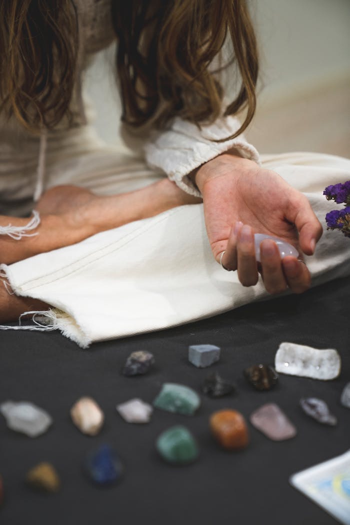 A person meditates with various healing crystals and stones, promoting tranquility and balance.